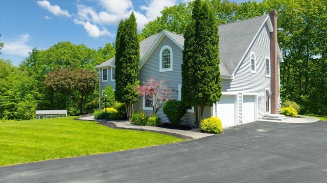 59 Sanderson Rd, Poland, ME 04274 - view of side of home with an attached garage, driveway, a lawn, a chimney, and roof with shingles