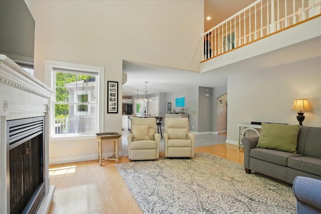 59 Sanderson Rd, Poland, ME 04274 - living room featuring a high ceiling, wood finished floors, a fireplace, baseboards, and a chandelier