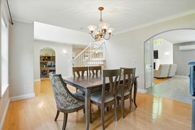 59 Sanderson Rd, Poland, ME 04274 - dining area featuring arched walkways, a wall mounted AC, light wood-style flooring, a chandelier, and ornamental molding