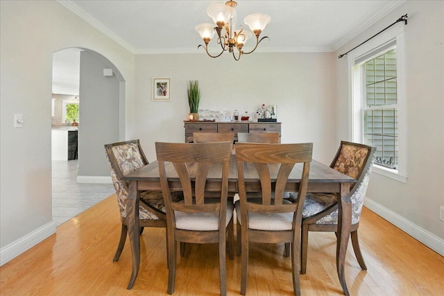 59 Sanderson Rd, Poland, ME 04274 - dining area featuring arched walkways, a chandelier, baseboards, crown molding, and light wood-style floors