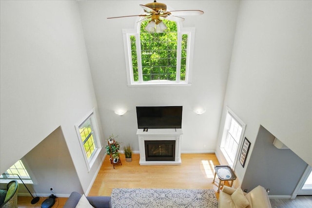 59 Sanderson Rd, Poland, ME 04274 - living room with a towering ceiling, a ceiling fan, wood finished floors, a glass covered fireplace, and baseboards