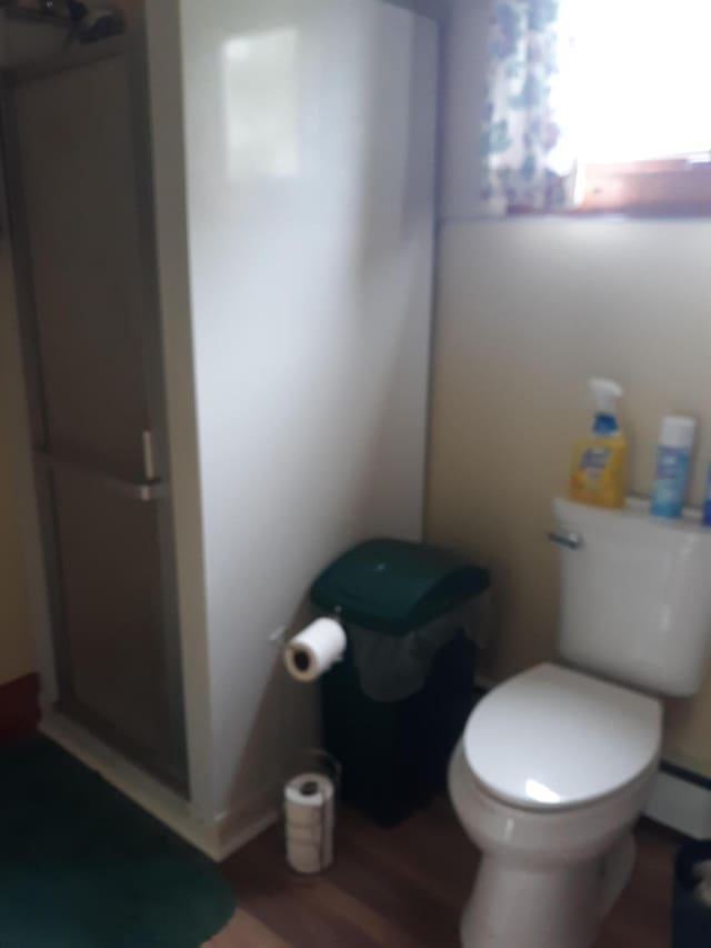 100 Bayside Rd, Ellsworth, ME 04605 - bathroom featuring toilet, a shower stall, wood finished floors, and a baseboard heating unit