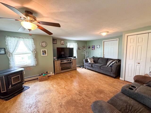 164 Mud Pond Road, Prentiss Twp T7 R3 Nbpp, ME 04487 - living area featuring a wood stove, a ceiling fan, a baseboard radiator, a textured ceiling, and light carpet