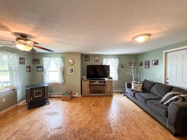 164 Mud Pond Road, Prentiss Twp T7 R3 Nbpp, ME 04487 - living area featuring a wood stove, a textured ceiling, a baseboard heating unit, ceiling fan, and baseboards