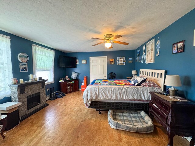 164 Mud Pond Road, Prentiss Twp T7 R3 Nbpp, ME 04487 - bedroom with a textured ceiling, a stone fireplace, ceiling fan, and wood finished floors