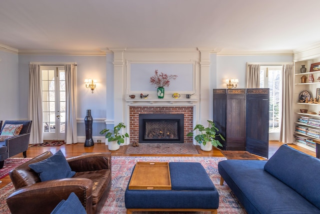 18 Bayside Dr, Belfast, ME 04915 - living area featuring crown molding, plenty of natural light, a brick fireplace, wood finished floors, and french doors