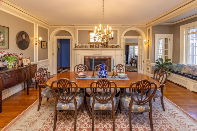 18 Bayside Dr, Belfast, ME 04915 - dining space with arched walkways, wood finished floors, a decorative wall, a chandelier, and a brick fireplace
