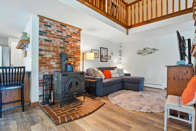 51 Four Wheel Dr, Brunswick, ME 04011 - living area with baseboard heating, a wood stove, wood finished floors, and a towering ceiling