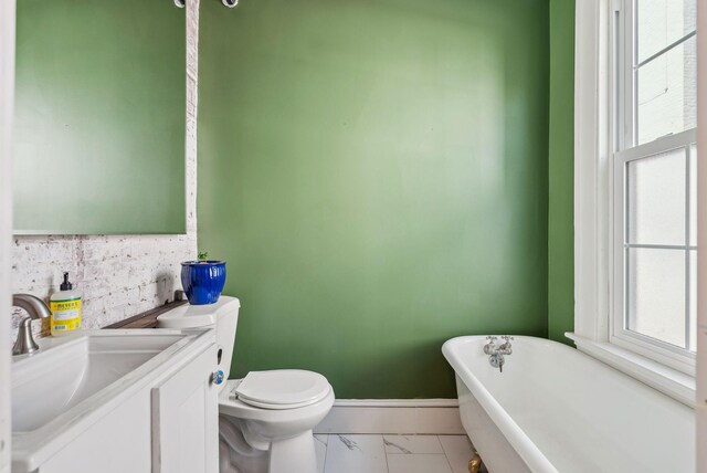 148 State St, Portland, ME 04101 - bathroom featuring a freestanding bath, marble look tile flooring, toilet, vanity, and baseboards