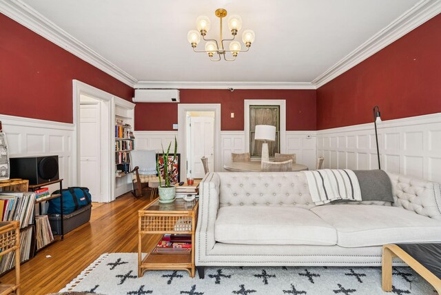 148 State St, Portland, ME 04101 - living room with a wall mounted air conditioner, ornamental molding, a chandelier, wood finished floors, and wainscoting