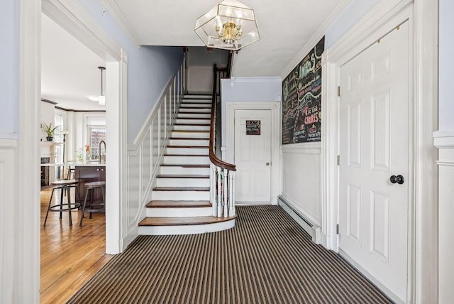 148 State St, Portland, ME 04101 - stairway featuring a baseboard radiator, a decorative wall, crown molding, a wainscoted wall, and a chandelier
