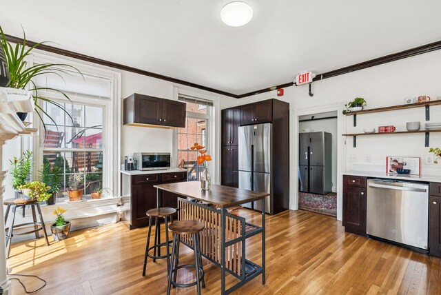 148 State St, Portland, ME 04101 - kitchen with appliances with stainless steel finishes, ornamental molding, dark brown cabinets, light wood-style flooring, and light countertops