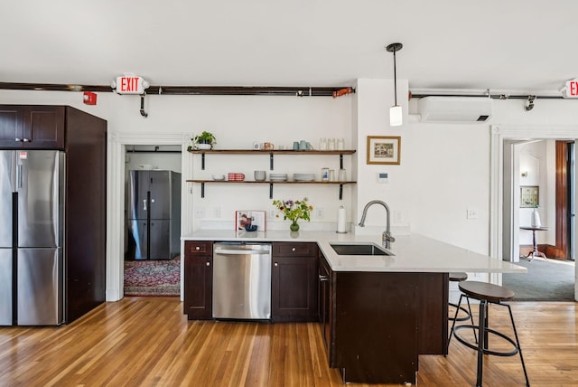 148 State St, Portland, ME 04101 - kitchen featuring appliances with stainless steel finishes, a sink, a wall mounted AC, a peninsula, and light wood-type flooring
