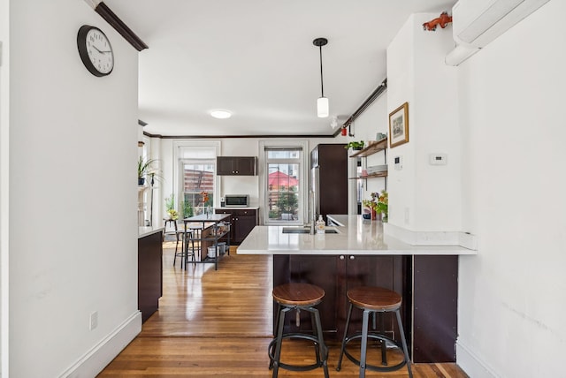 148 State St, Portland, ME 04101 - kitchen featuring a peninsula, wood finished floors, a breakfast bar, light countertops, and baseboards