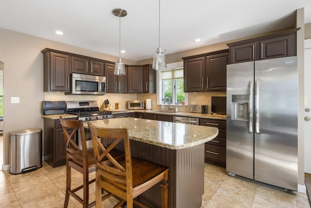 216 Monroe Rd, Winterport, ME 04496 - kitchen with stainless steel appliances, dark brown cabinets, backsplash, light stone counters, and a center island