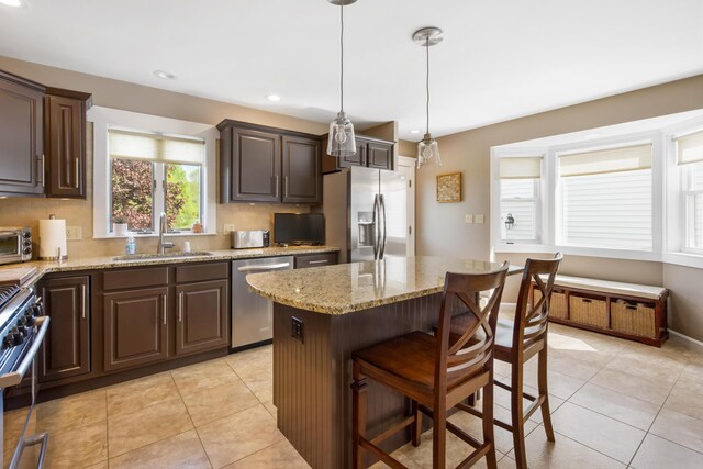 216 Monroe Rd, Winterport, ME 04496 - kitchen with a sink, appliances with stainless steel finishes, dark brown cabinets, a kitchen breakfast bar, and light stone counters