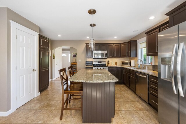 216 Monroe Rd, Winterport, ME 04496 - kitchen with stainless steel appliances, arched walkways, a sink, dark brown cabinetry, and a kitchen island