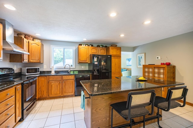 183 Buckfield Rd, Turner, ME 04282 - kitchen with black appliances, wall chimney exhaust hood, a sink, a breakfast bar, and recessed lighting