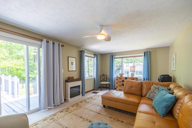 183 Buckfield Rd, Turner, ME 04282 - living area with a glass covered fireplace, a textured ceiling, ceiling fan, and baseboards
