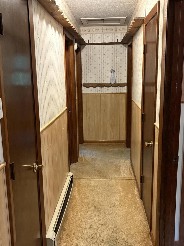 16 Evergreen Estates Rd, Nobleboro, ME 04555 - corridor featuring attic access, a baseboard heating unit, light colored carpet, wainscoting, and wooden walls