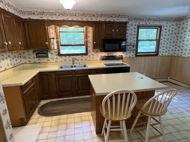 16 Evergreen Estates Rd, Nobleboro, ME 04555 - kitchen with black appliances, wallpapered walls, light countertops, wainscoting, and a breakfast bar