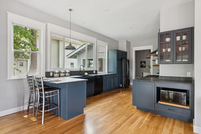 217 Ocean Ave, Portland, ME 04103 - kitchen featuring black appliances, a peninsula, a kitchen breakfast bar, light wood finished floors, and glass insert cabinets