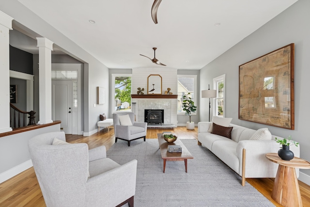 217 Ocean Ave, Portland, ME 04103 - living room featuring light wood-type flooring, a fireplace with raised hearth, baseboards, and decorative columns