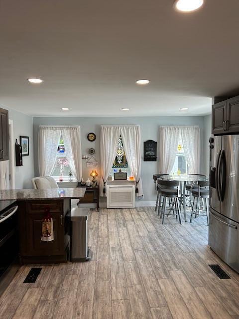 48 Allen St, Bangor, ME 04401 - kitchen with stainless steel fridge with ice dispenser, light wood-style flooring, recessed lighting, and dark brown cabinets