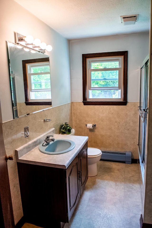 130 Davis Rd, Fairfield, ME 04937 - full bath with baseboard heating, tile walls, healthy amount of natural light, toilet, and vanity