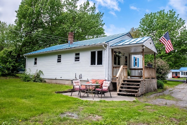 130 Davis Rd, Fairfield, ME 04937 - back of property with a patio, a chimney, a lawn, a wooden deck, and metal roof