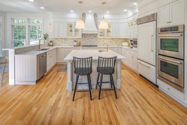 20 Doe Dr, Eliot, ME 03903 - kitchen with stainless steel appliances, custom range hood, a sink, light wood-type flooring, and a kitchen breakfast bar