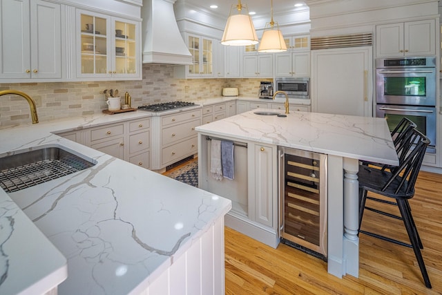 20 Doe Dr, Eliot, ME 03903 - kitchen with custom exhaust hood, built in appliances, a sink, beverage cooler, and light wood-style flooring