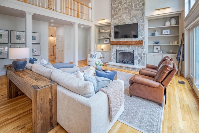 20 Doe Dr, Eliot, ME 03903 - living room featuring wood finished floors, a towering ceiling, decorative columns, a fireplace, and baseboards
