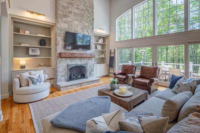 20 Doe Dr, Eliot, ME 03903 - living room with a high ceiling, a stone fireplace, built in shelves, and light wood-style flooring