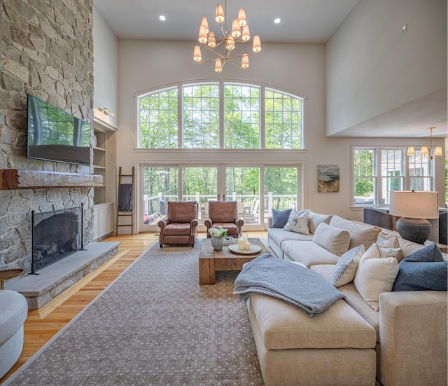 20 Doe Dr, Eliot, ME 03903 - living room featuring a chandelier, a towering ceiling, wood finished floors, a stone fireplace, and recessed lighting