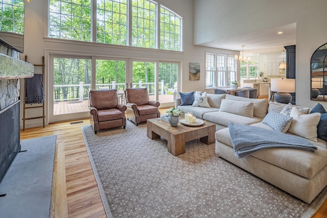 20 Doe Dr, Eliot, ME 03903 - living area with a chandelier, a towering ceiling, light wood-type flooring, healthy amount of natural light, and a fireplace