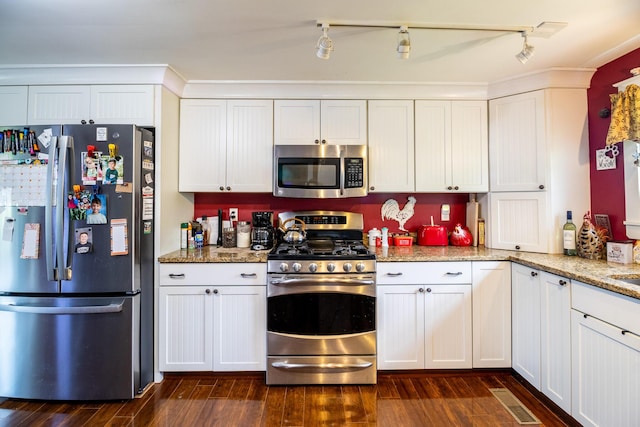 590 Main St, East Machias, ME 04630 - kitchen with stainless steel appliances, dark wood-style flooring, light stone countertops, and white cabinetry