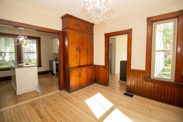 12 Park Ave, Newport, ME 04953 - unfurnished dining area featuring a chandelier, light wood finished floors, a sink, plenty of natural light, and wainscoting
