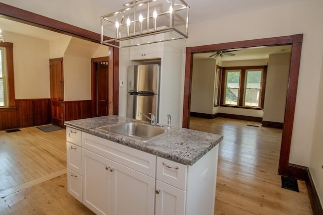 12 Park Ave, Newport, ME 04953 - kitchen featuring freestanding refrigerator, a sink, light wood-style floors, wainscoting, and white cabinets