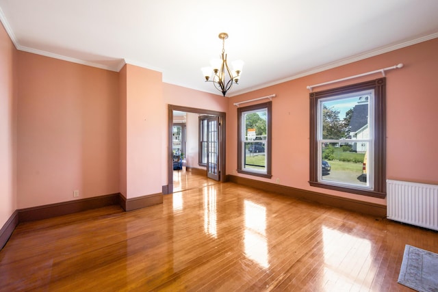 123 Main St, Newport, ME 04953 - empty room with radiator heating unit, a chandelier, wood finished floors, crown molding, and baseboards