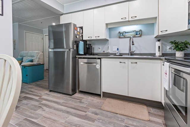 131 Temple Ave Unit 26, Old Orchard Beach, ME 04064 - kitchen with stainless steel appliances, white cabinetry, dark countertops, a sink, and crown molding