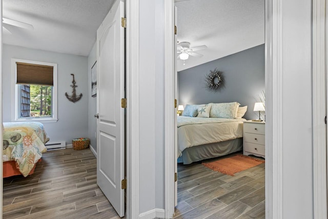 131 Temple Ave Unit 26, Old Orchard Beach, ME 04064 - bedroom with wood finish floors, baseboard heating, a textured ceiling, baseboards, and a ceiling fan