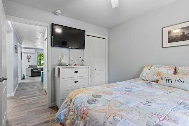 131 Temple Ave Unit 26, Old Orchard Beach, ME 04064 - bedroom featuring an AC wall unit, light wood-style flooring, a closet, and baseboards