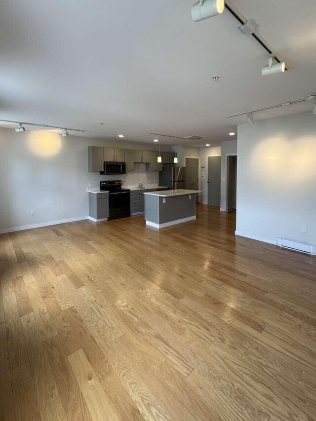 65 Munjoy St Unit 4, Portland, ME 04101 - unfurnished living room with track lighting, light wood-style floors, a baseboard radiator, baseboards, and recessed lighting