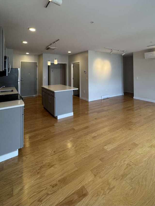 65 Munjoy St Unit 4, Portland, ME 04101 - kitchen with a wall mounted air conditioner, a sink, a kitchen island, light countertops, and open floor plan