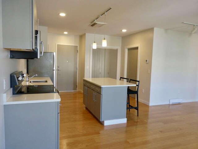 65 Munjoy St Unit 4, Portland, ME 04101 - kitchen with a kitchen bar, a center island, light wood-style floors, recessed lighting, and light countertops