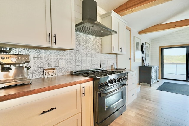 32 Water St, Lubec, ME 04652 - kitchen featuring high end stove, wall chimney range hood, backsplash, light wood-style floors, and white cabinetry