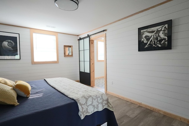 32 Water St, Lubec, ME 04652 - bedroom featuring a barn door, wood finished floors, and wooden walls