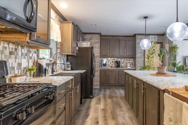 833 Sedgwick Ridge Rd, Sedgwick, ME 04676 - kitchen with black appliances, tasteful backsplash, light wood-style floors, pendant lighting, and light stone countertops