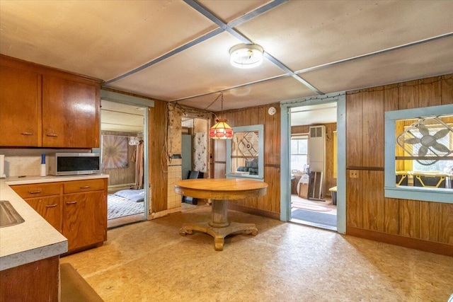 833 Sedgwick Ridge Rd, Sedgwick, ME 04676 - kitchen with stainless steel microwave, brown cabinets, light countertops, wooden walls, and light floors